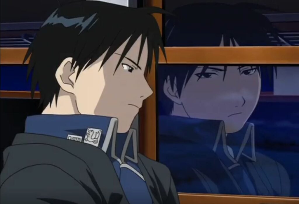 Visual storytelling for emotion. Roy Mustang's angry expression is one we are familiar with. But his reflection in the train window shows a different angle: sadness.
